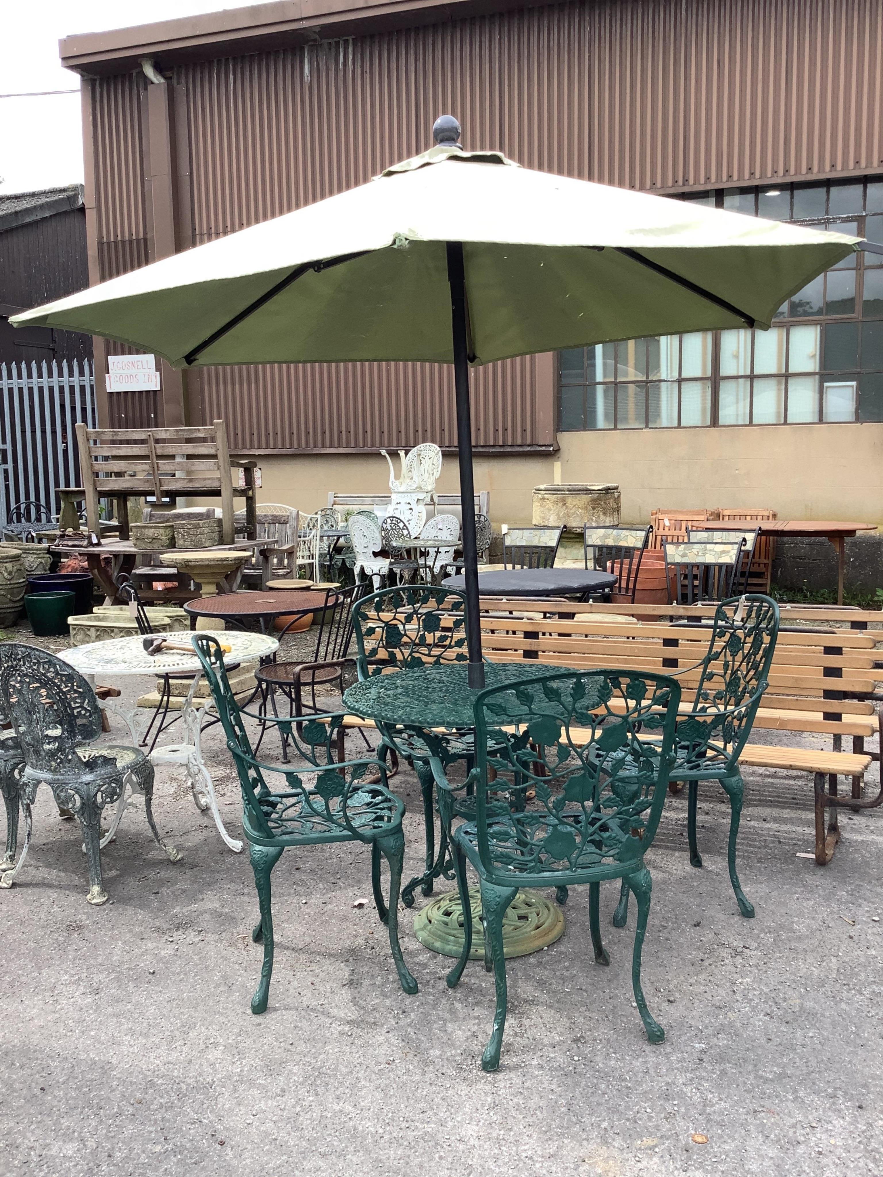 A Victorian style painted aluminium circular garden table, diameter 80cm, height 71cm, four similar garden armchairs, parasol with cast metal base